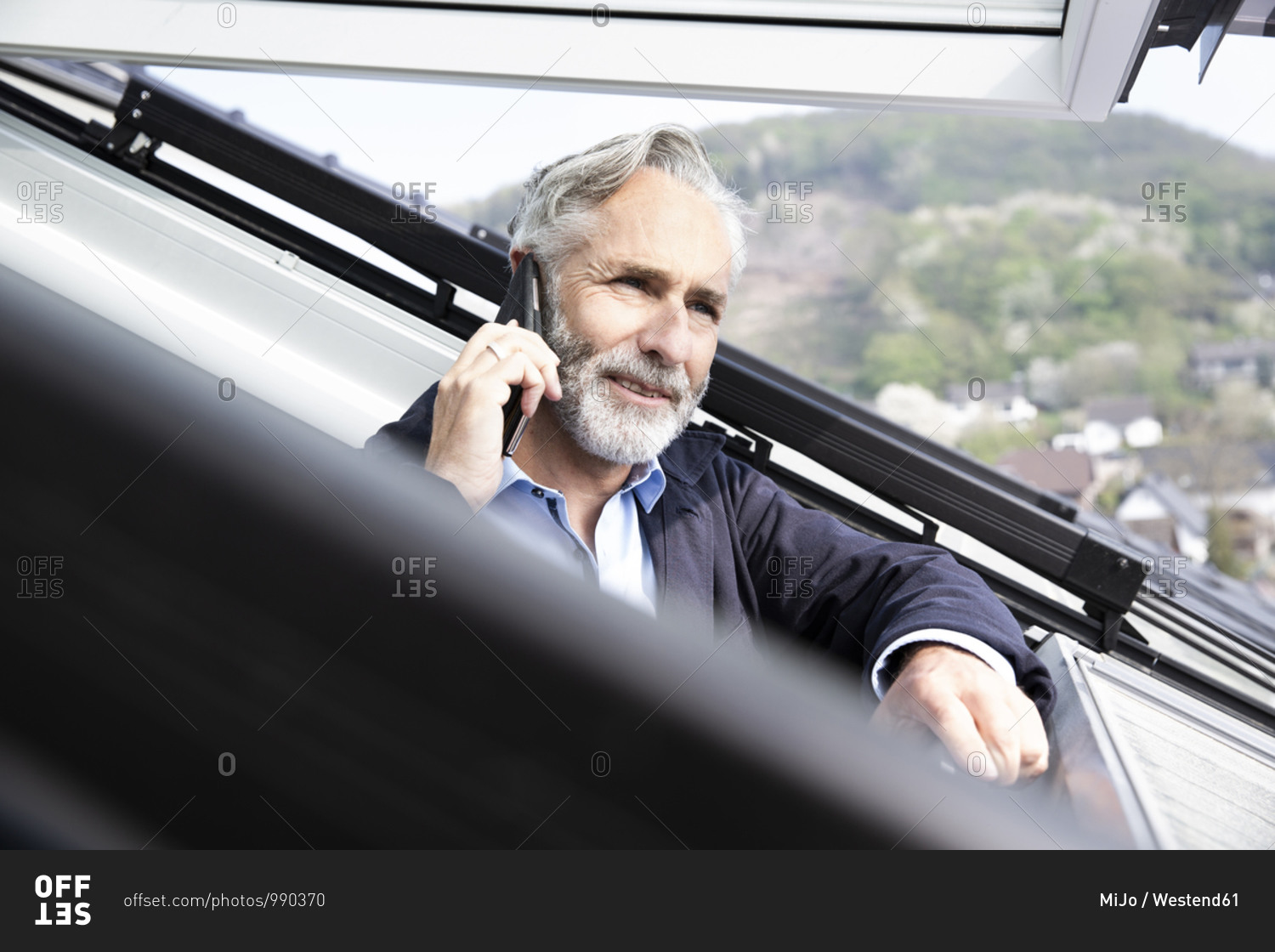 Close-up of male architect talking over smart phone in house seen through window