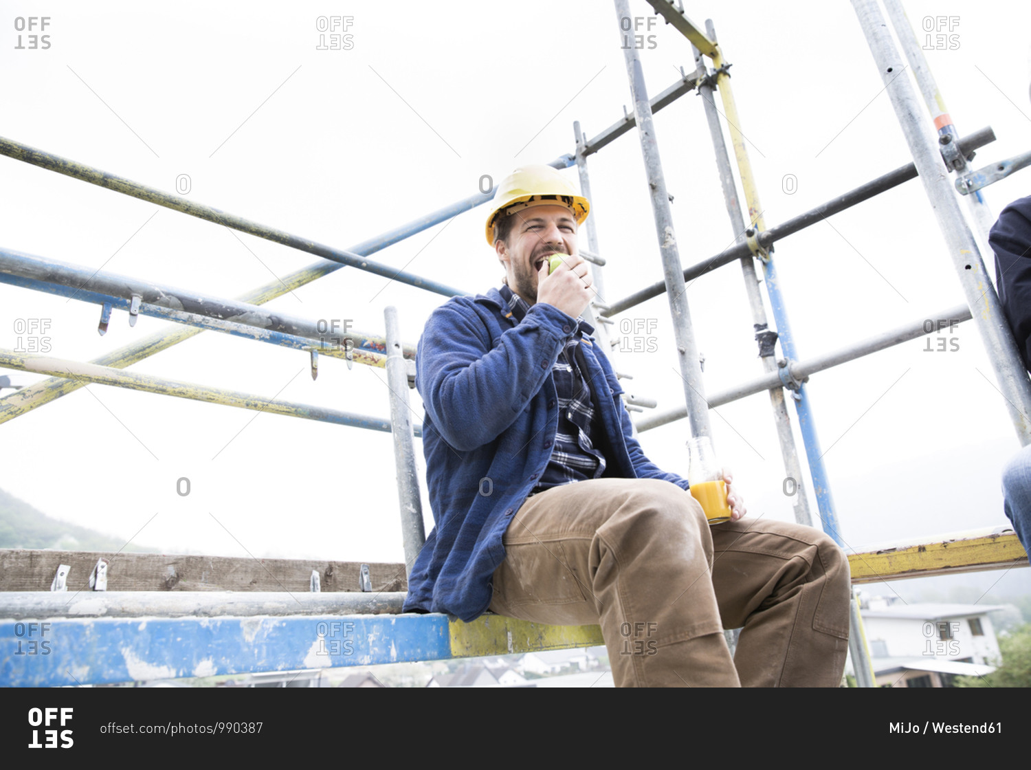 Ear protectors on wood with male worker carrying wood in background at construction site
