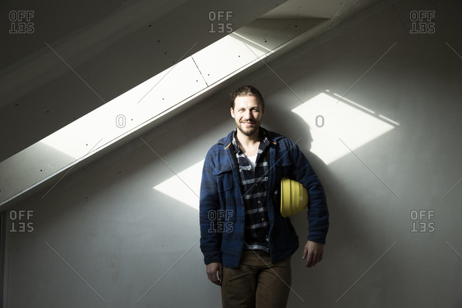 Construction worker with hardhat standing against wall in renovating house