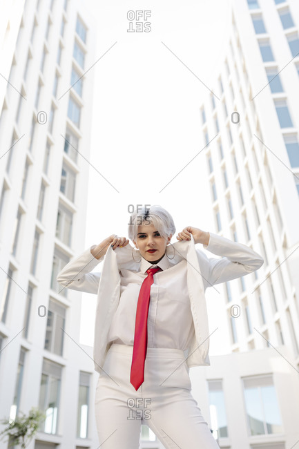Cool young woman wearing white suit standing against buildings in city