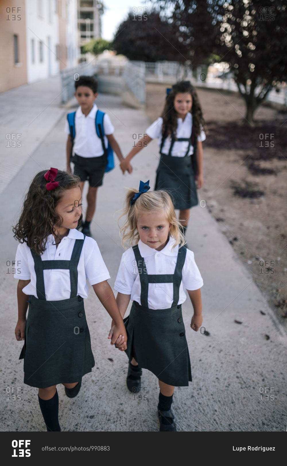 Group of four children going to school holding hands