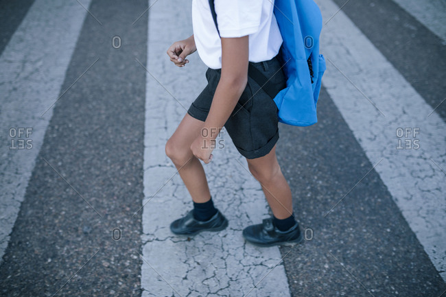 Student boy with backpack crossing a zebra crossing