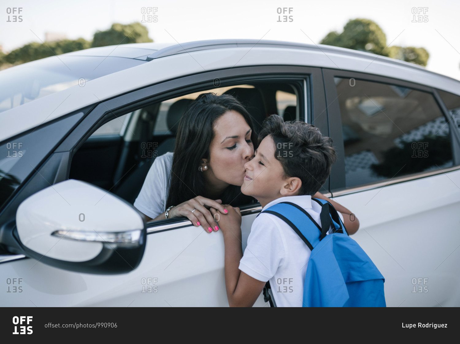 School boy saying goodbye to his mother in the car