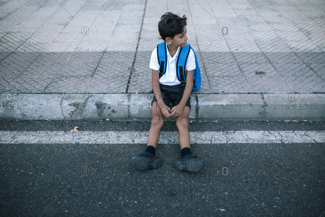 Boy in uniform and backpack waiting at the exit from school.