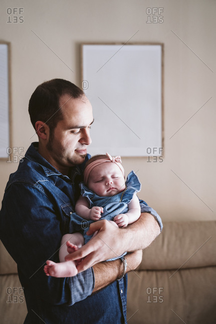 Father carrying sleeping baby girl in living room at home