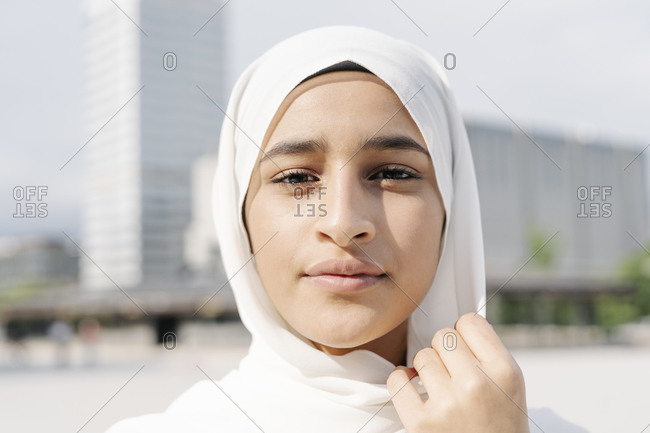 Confident teenage girl wearing headscarf in city during sunny day