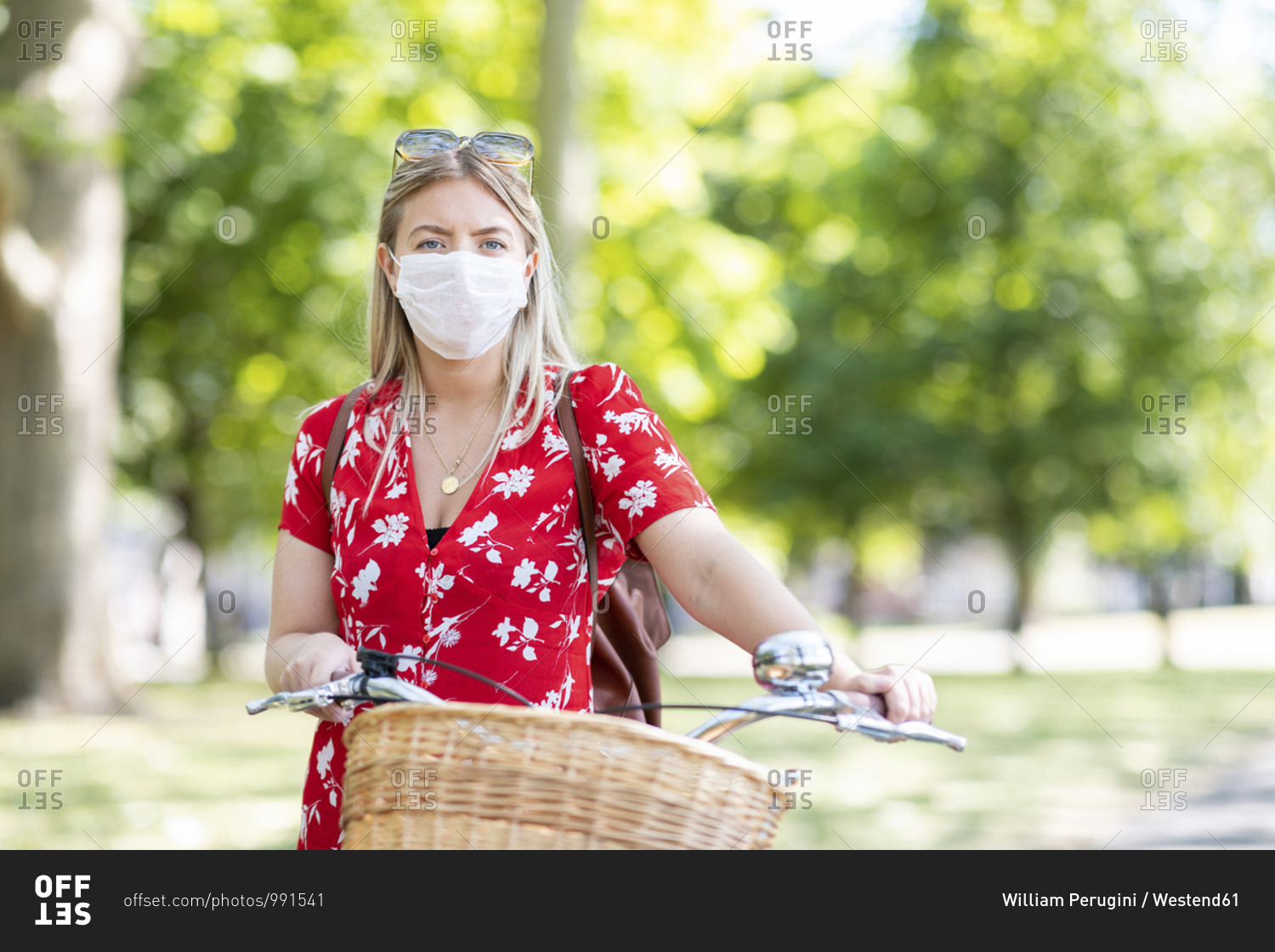 Woman wearing mask while standing with bicycle in public park