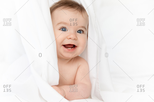 Close up of happy baby face peeking behind white sheet