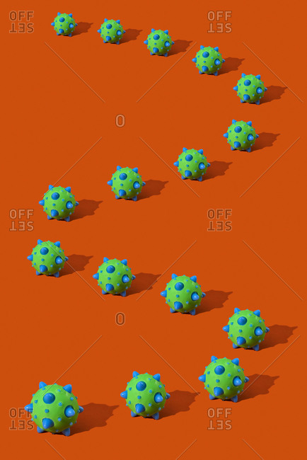 A representation of some SARS-CoV-2 virions, that cause the covid-19, forming a meandering line on an orange background