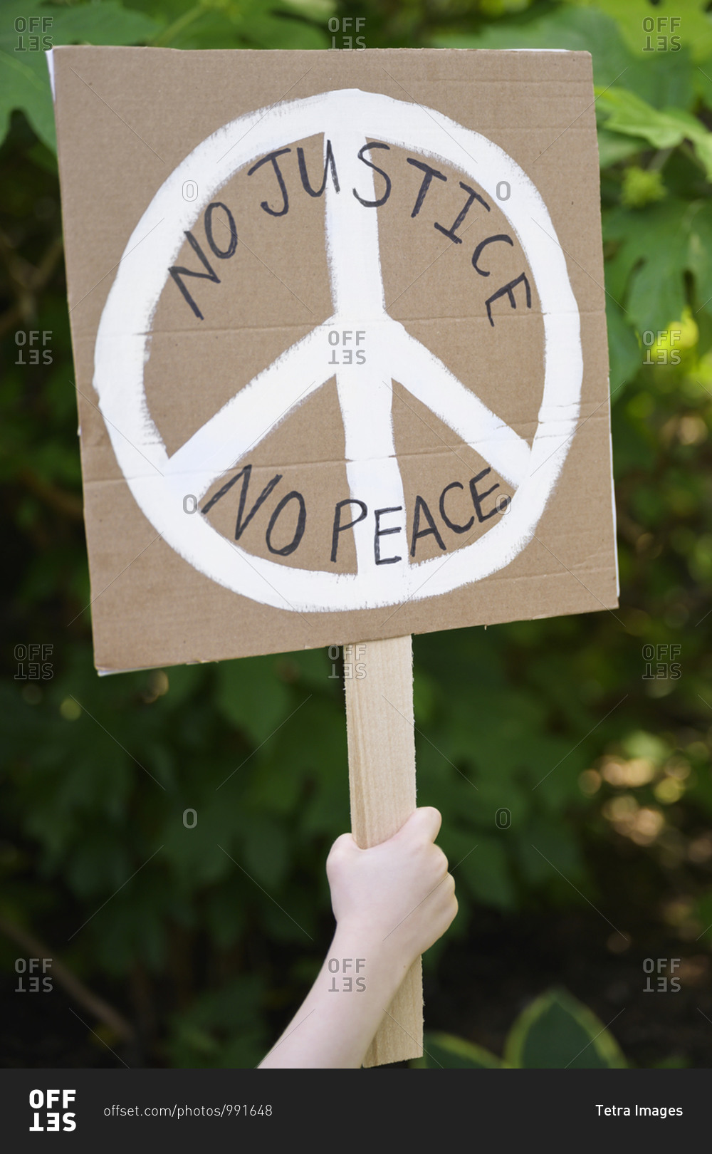 Child\'s hand holding No justice, no peace sign