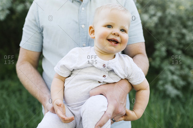 Outdoor portrait of baby boy carried by his father outdoors