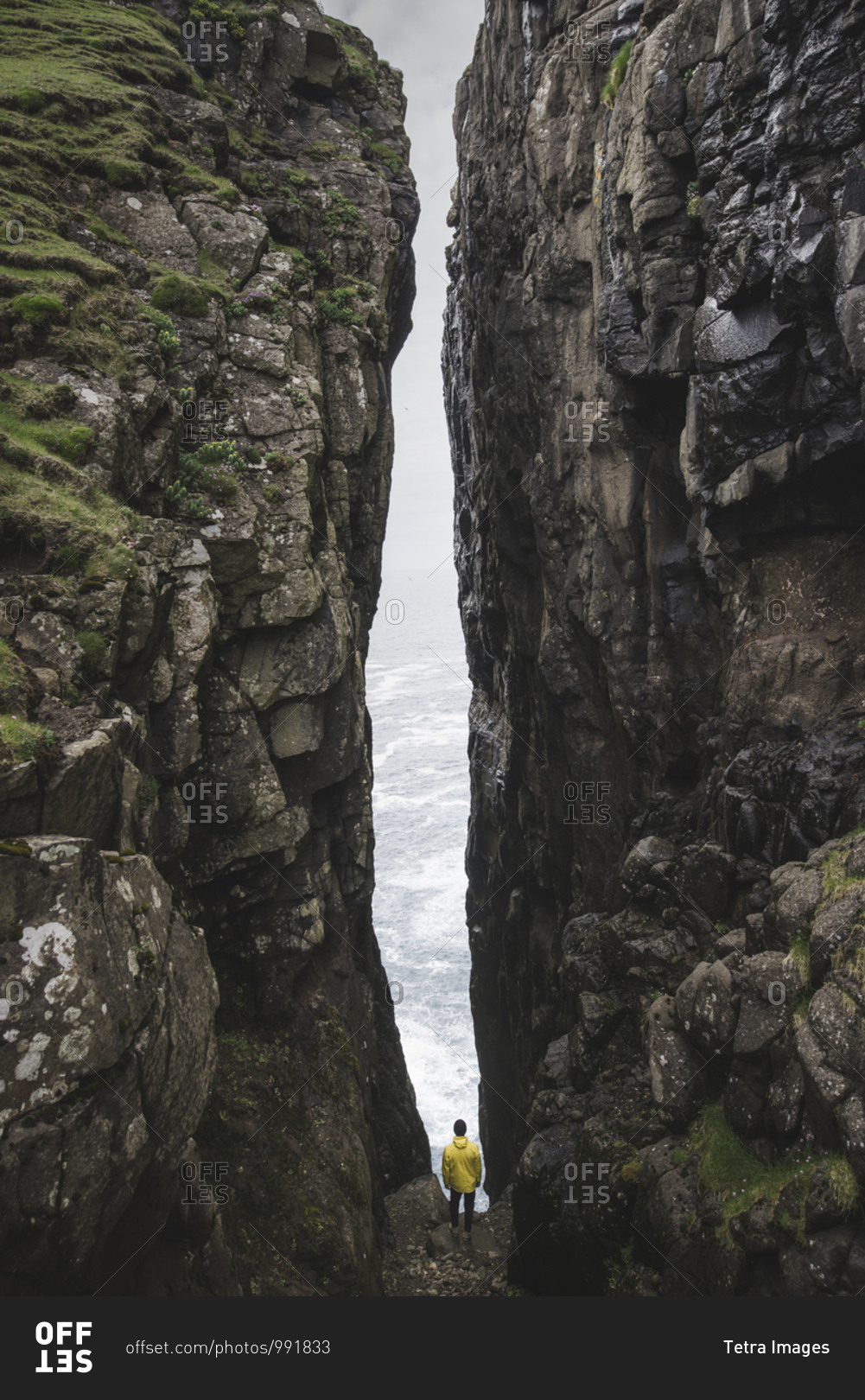 Denmark, Faroe Islands, Sorvagur, Man standing between two cliffs
