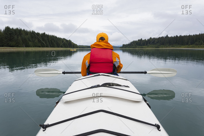 Woman sea kayaking calm waters of an inlet in a national park.
