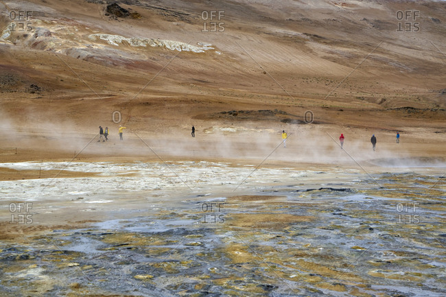 Tourists at Hverir geothermal spot with mud pools and steaming fumaroles emitting sulfuric gas in Iceland