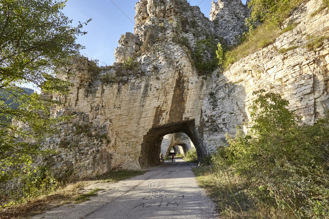 Boys riding bikes on road leading through The Wonderful Rocks in the Balkan Mountains, Bulgaria