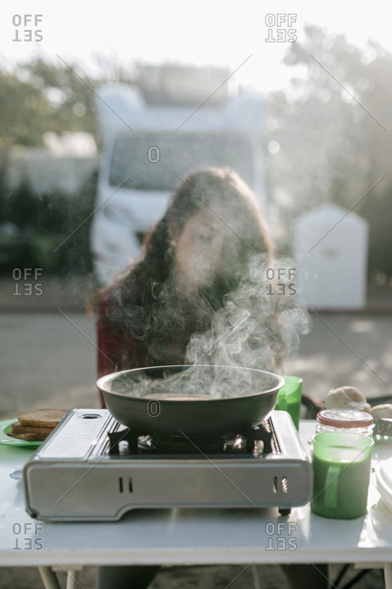 Young woman cooking in a portable kitchen on a camping site