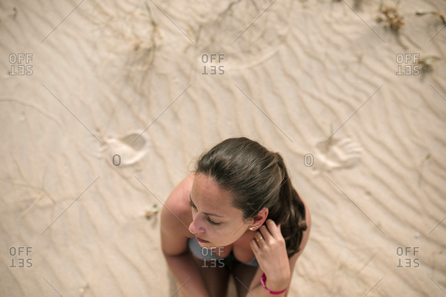 Portrait of young woman bird eye view sitting on beach sand