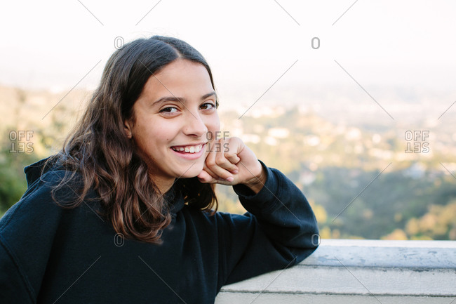 Twelve year old girl smiles for a cheesy portrait at a scenic overlook