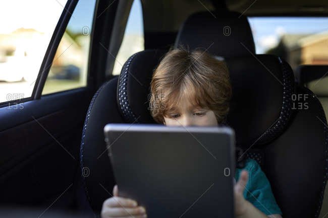 Boy using digital tablet while traveling in car