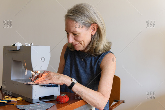 Senior woman smiling while sewing masks at home