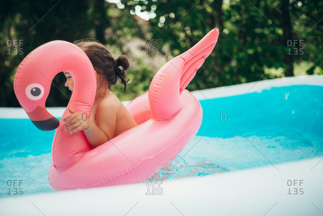 Happy child playing in the pool with flamingo water toy