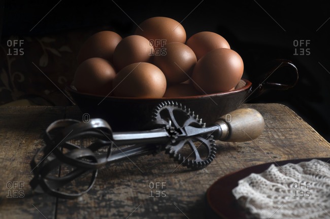 Farm house fresh eggs on a wooden table with iron whisk