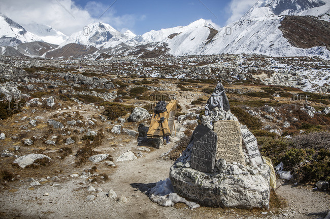 A porter carries goods past prayer stones in Nepal\'s Khumbu Valley.