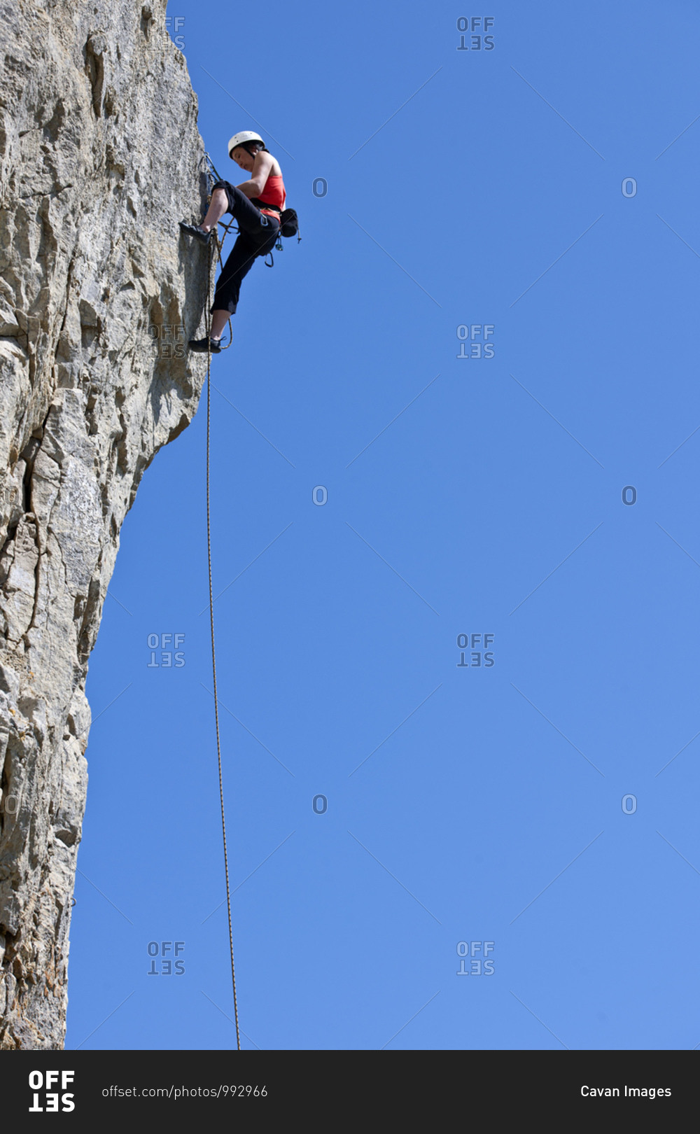 Woman climbing limestone rock face in Swanage / UK