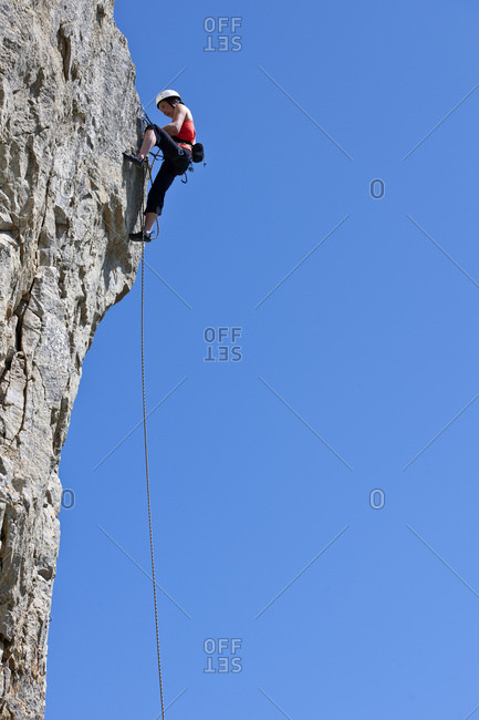 Woman climbing limestone rock face in Swanage / UK