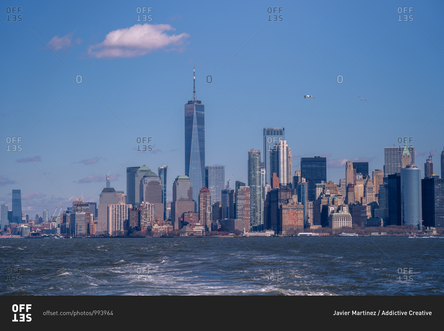 New York cityscape with skyscrapers and modern buildings seen from floating boat against blue sky