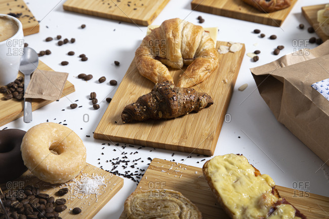 Top view of breakfast table full of assorted pastries, sandwiches and coffee served on wooden boards