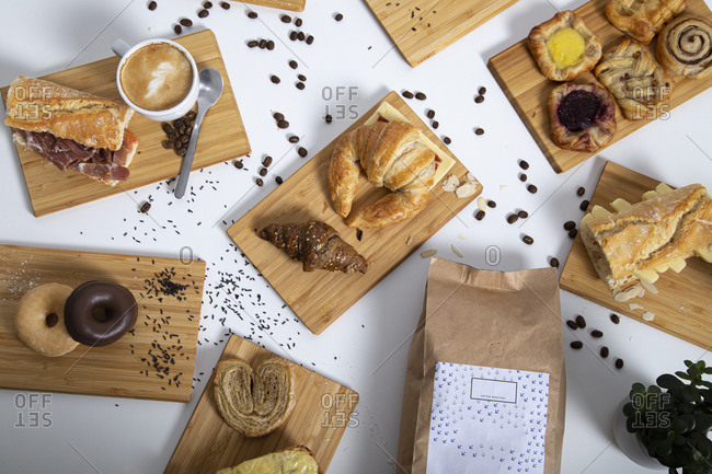 Top view of breakfast table full of assorted pastries, sandwiches and coffee served on wooden boards