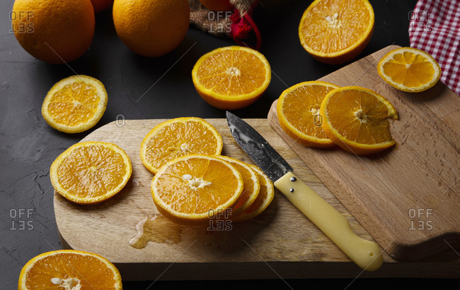 From above composition of halves of fresh oranges on wooden boards and mesh bag near glass jar with orange custard and plastic squeezer