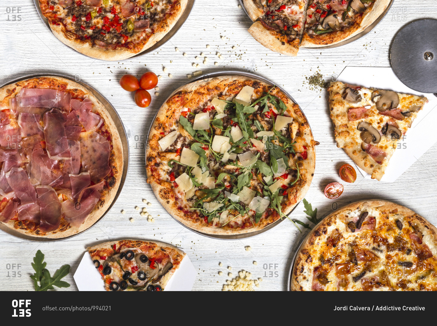Top view of delicious pizzas with various meat and vegetables placed on white wooden table in cafe