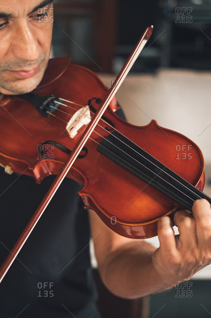 Cropped unrecognizable talented focused Hispanic male violinist playing violin during rehearsal
