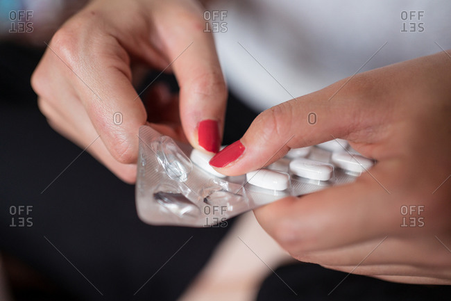 Unhealthy cropped unrecognizable female sitting on bed treating cold with medicine