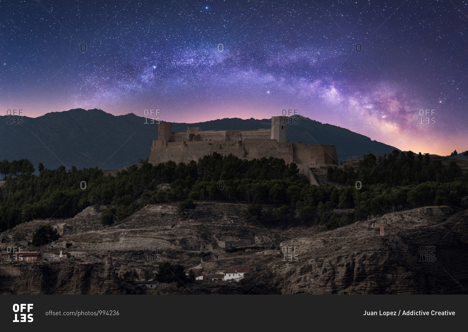 Castle on rough rocky mountain under spectacular scenery with luminous sky and Milky Way