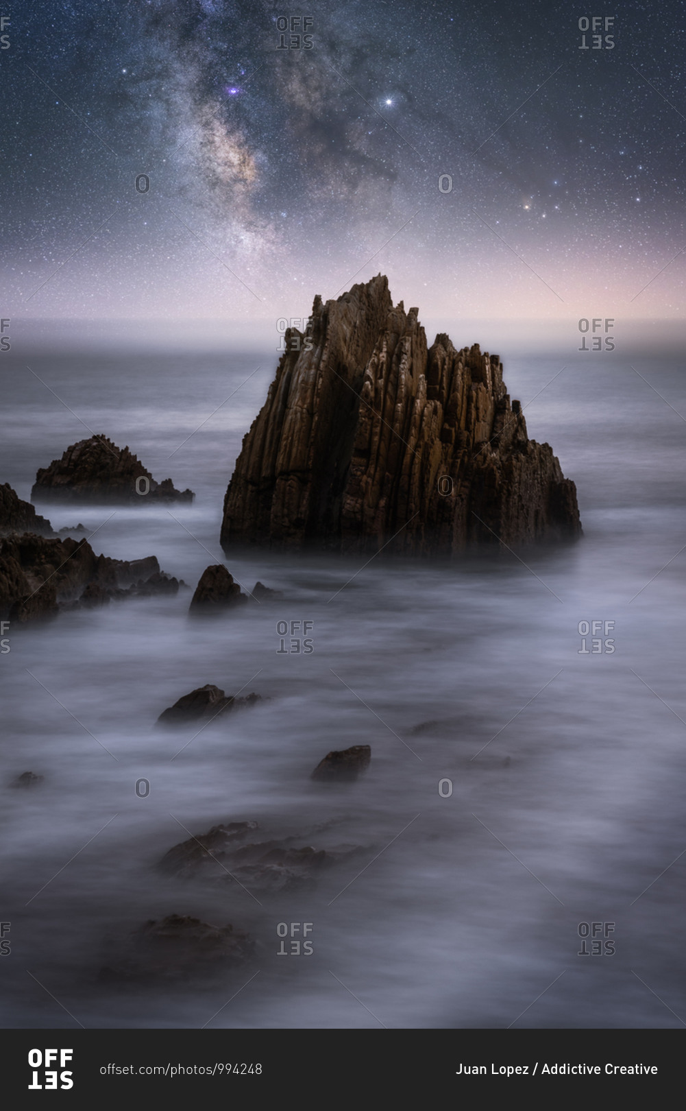 Amazing scenery of sea coast with calm water and rocky cliffs under dark sky with Milky Way
