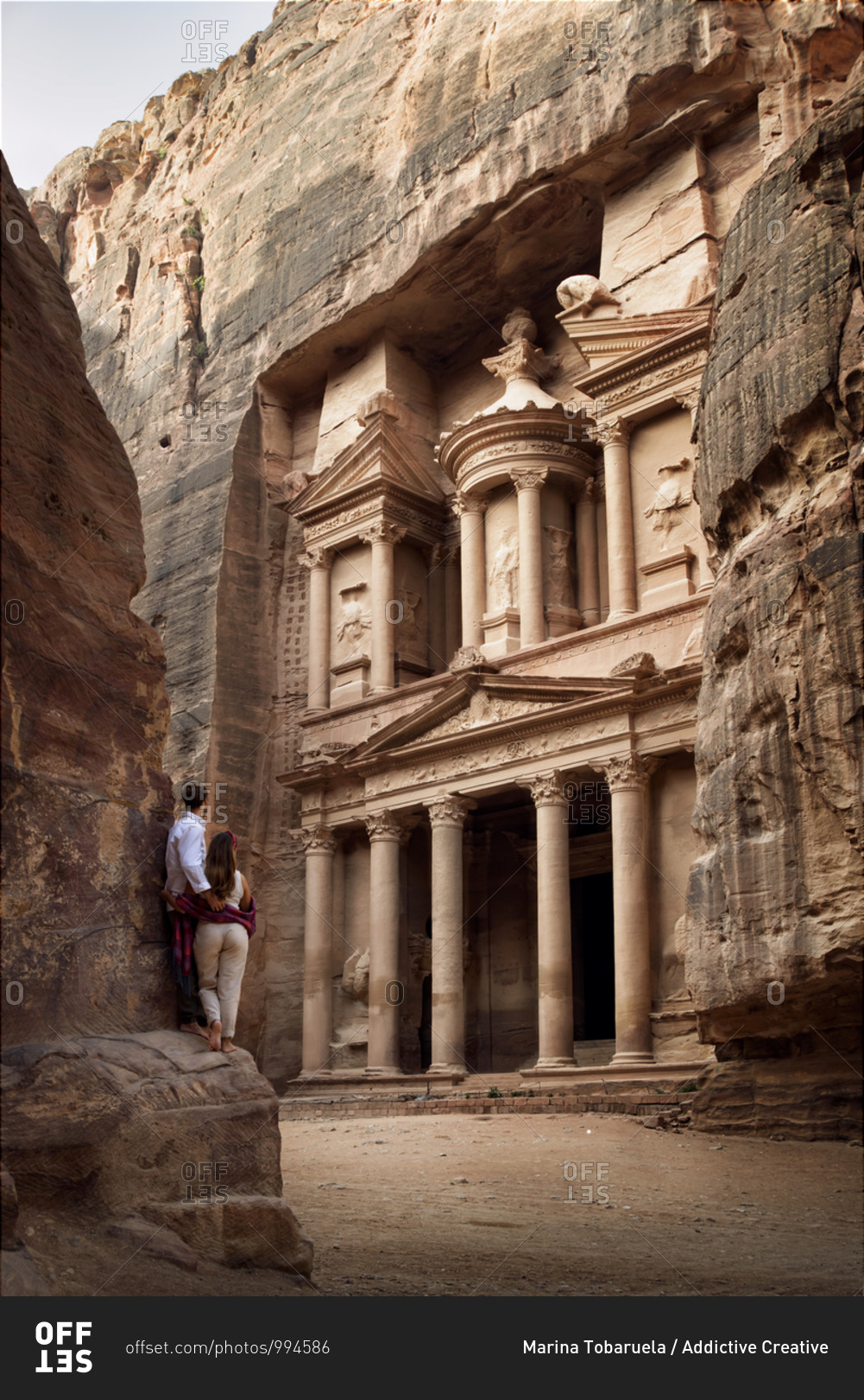 Back view of loving couple of tourists hugging and admiring view old ornamental facade of Al Khazneh temple in Jordan