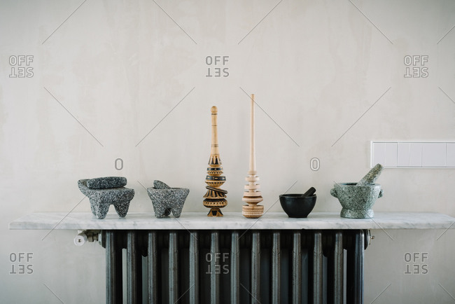Various kitchen utensils including mortars with pestles arranged in row on marble counter near wall