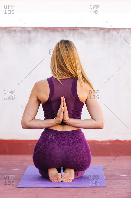 Back view of unrecognizable female meditating in Vajrasana with Namaste gesture behind back