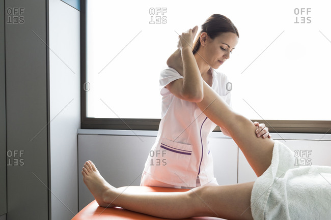 Female physiotherapist stretching leg of female patient