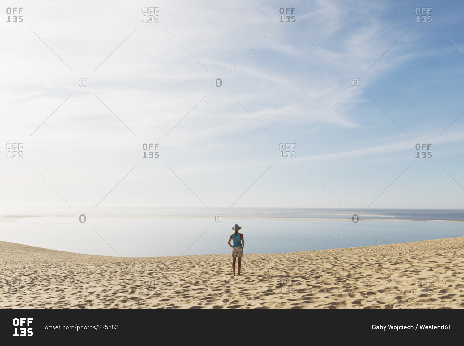 Woman looking at Atlantic ocean while standing on beach during sunny day- Nouvelle-Aquitaine- France