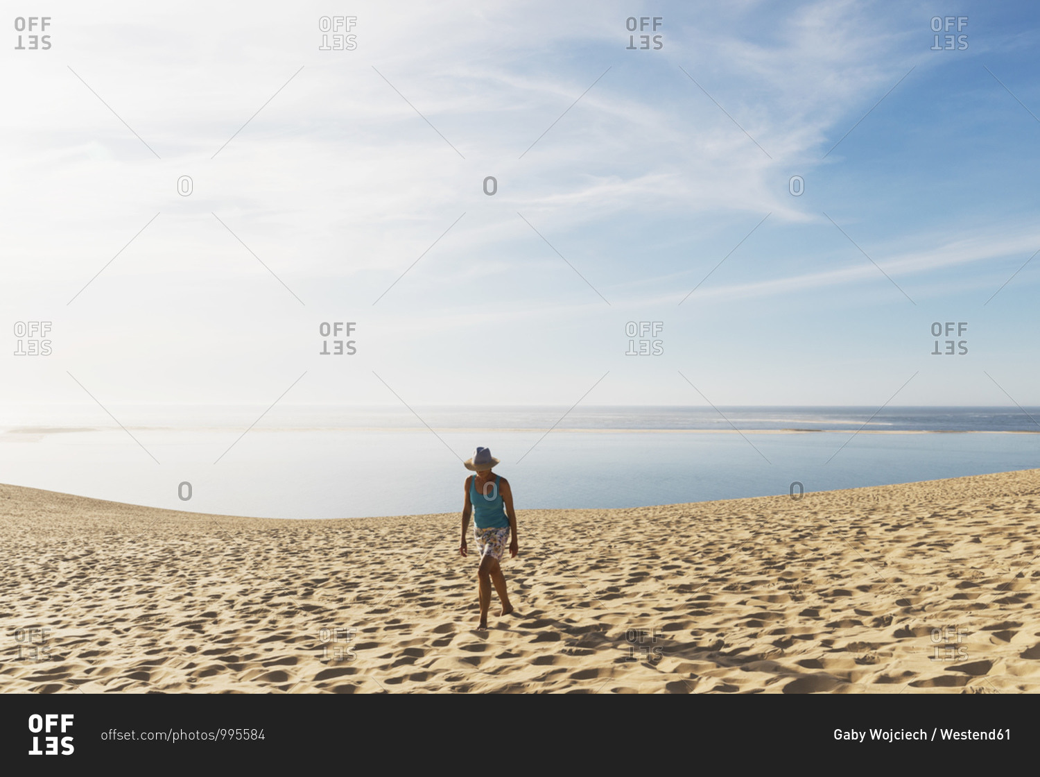 Woman walking on sand dunes at beach against sky- Nouvelle-Aquitaine- France