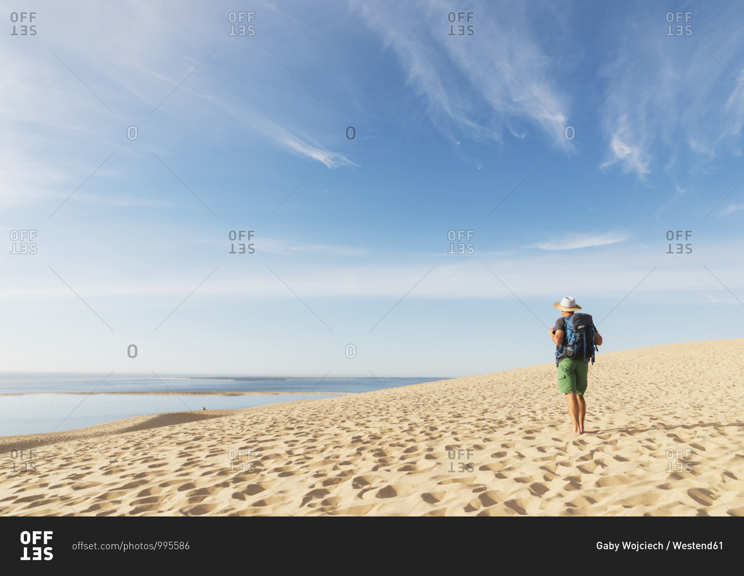 Senior man with backpack looking at Atlantic ocean while standing on beach- Nouvelle-Aquitaine- France
