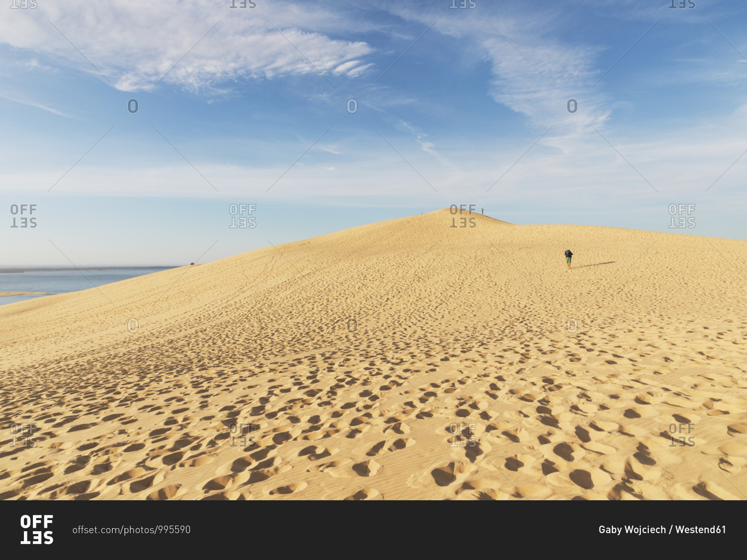 Mid distance view of man walking on sand dune against sky- Nouvelle-Aquitaine- France