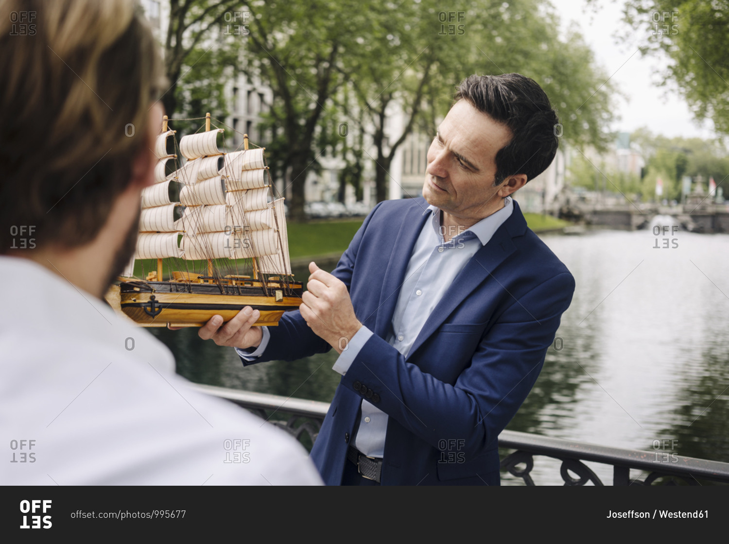 Mature businessman holding model sailing ship on a bridge