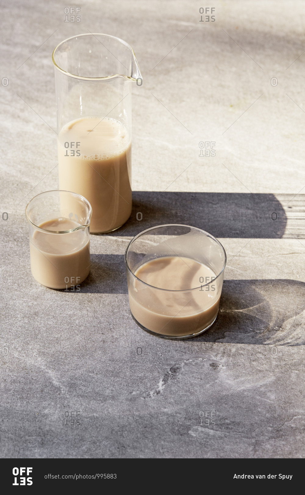 Three glass containers with long shadows filled with milk alternatives