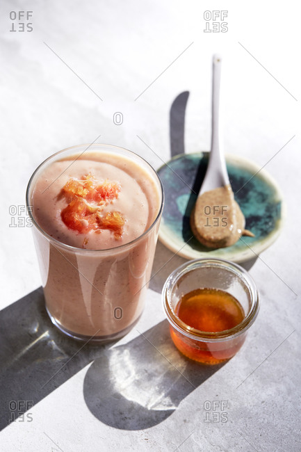 Peach and orange lassi with honey and orange segments on the side