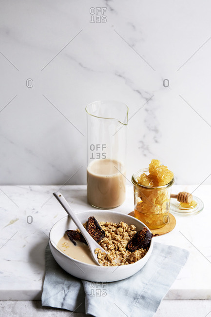 Homemade granola with dried figs, fresh honeycomb and nut milk